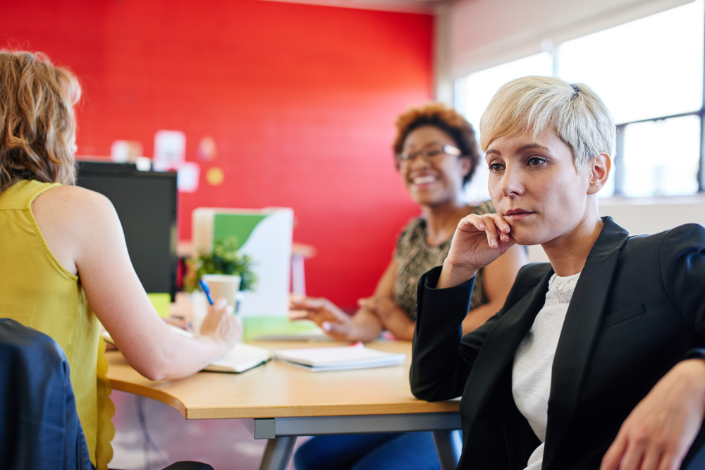 Confident female designer sitting at her desk for a brainstorming in red creative office space